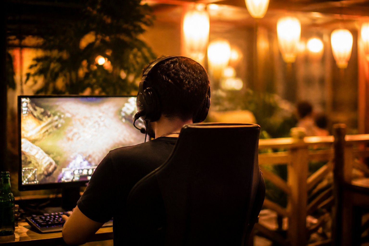 A player in headphones smiling at a lit gaming station during a good moment in a match